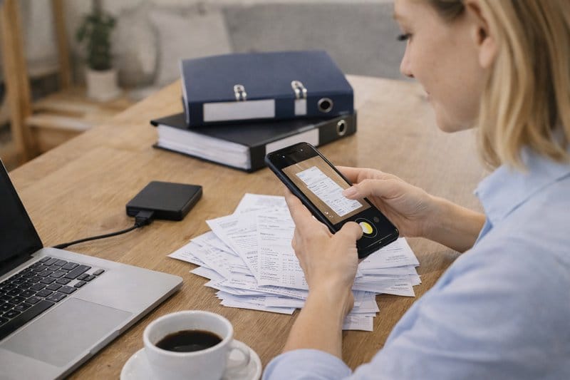 Ondernemer maakt een digitale back-up van haar administratie aan de keukentafel met documenten en externe schijf.